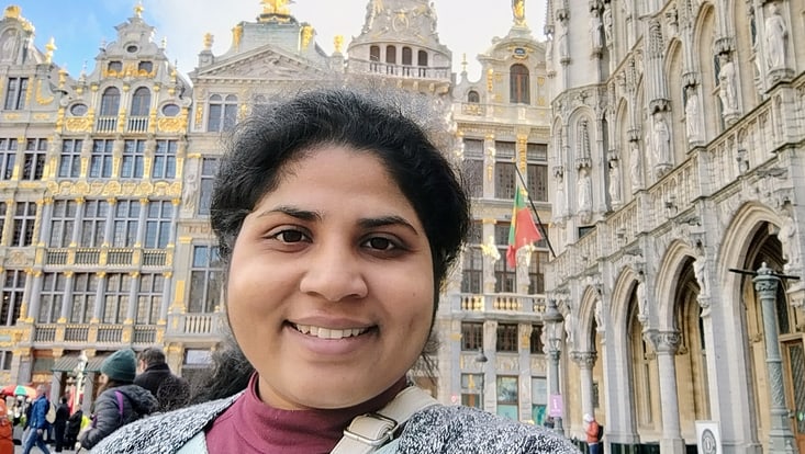 Doctoral Researcher in the foreground standing in front of old fashioned buildings in the historic centre of Brussels